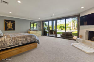 PRIMARY BEDROOM WITH ACCORDIAN GLASS DOORS LEADING TO POOL AND COVERED PATIO